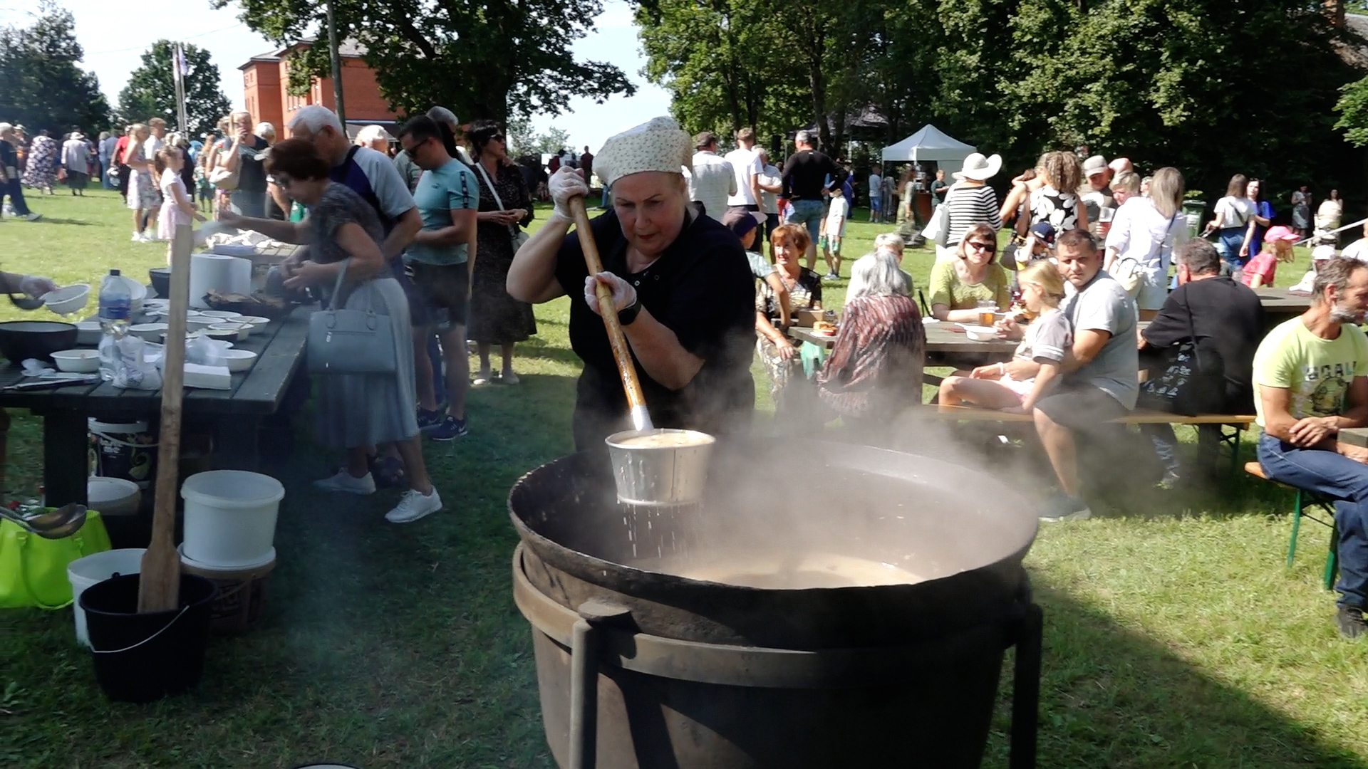 Sieviete brīvdabas festivālā pasniedz zupu no lielā katla