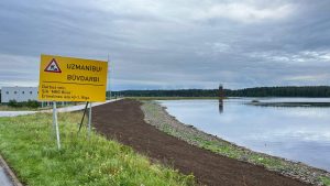 Dambja atjaunošanas darbu vieta Ogrē ar brīdinājuma zīmi "UZMANĪBU! BŪVDARBI!".