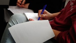 Divi cilvēki pieraksta piezīmes kladēs un uz lapām mācību vai semināra laikā.