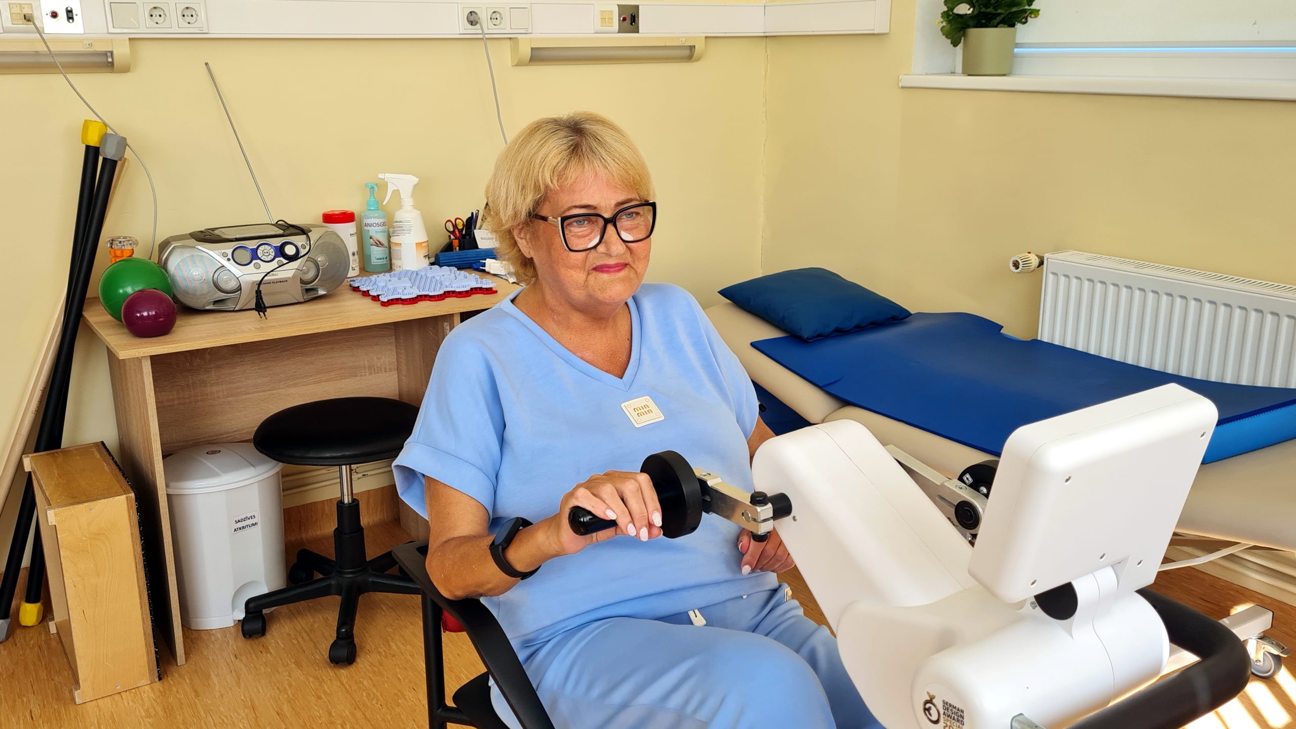 Sieviete rehabilitācijas nodarbībā izmanto vingrošanas iekārtu