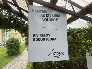 Plakāts latgaliski ar uzrakstu “Pīdzymu ar divejom volūdom – div reizis boguotuo ka”