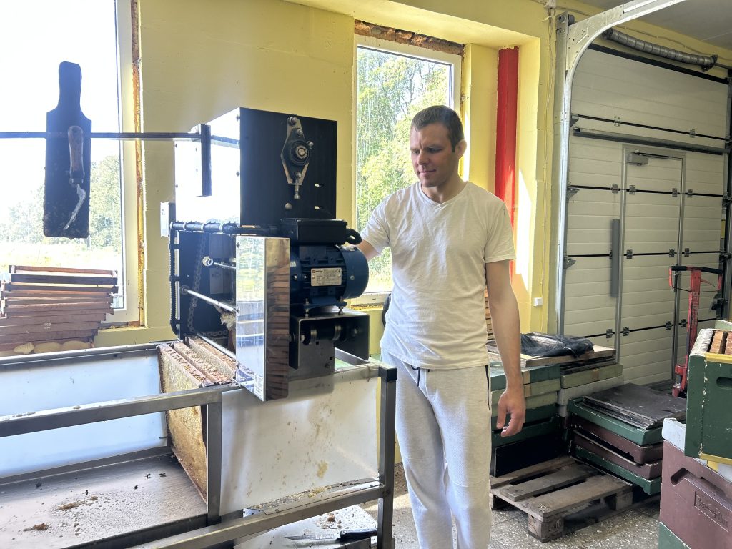 Biškopis Agnis Mednis strādā pie medus apstrādes mašīnas.