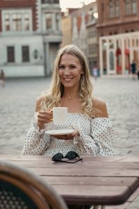 Katrīna tur Katrīnas Keramikas porcelāna krūzi ar zelta rokturi Vecrīgā