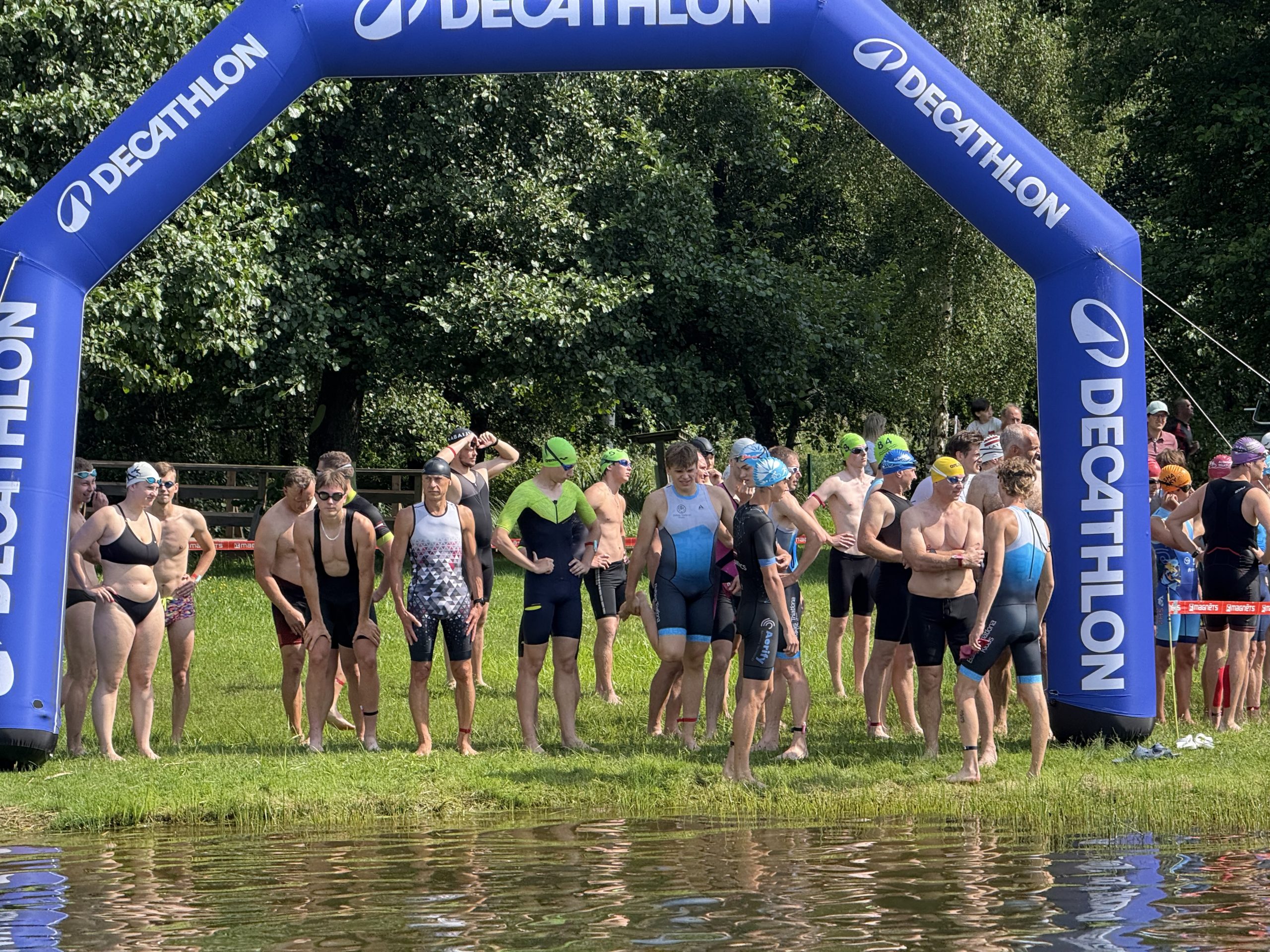 Dalībnieki gatavojas peldēšanas startam zem “Decathlon” arkas triatlona sacensībās