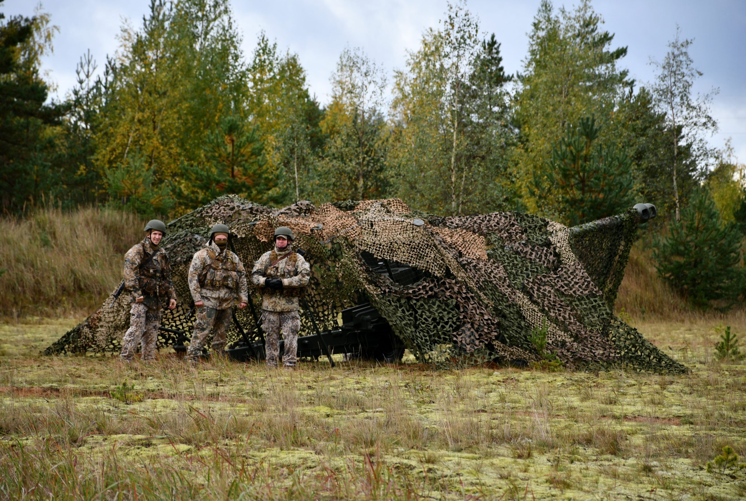 Karavīri pie maskētas tehnikas militārajās mācībās mežā
