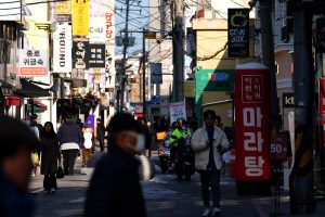 Dienvidkorejas pilsētas iela ar gājējiem un korejiešu izkārtnēm.