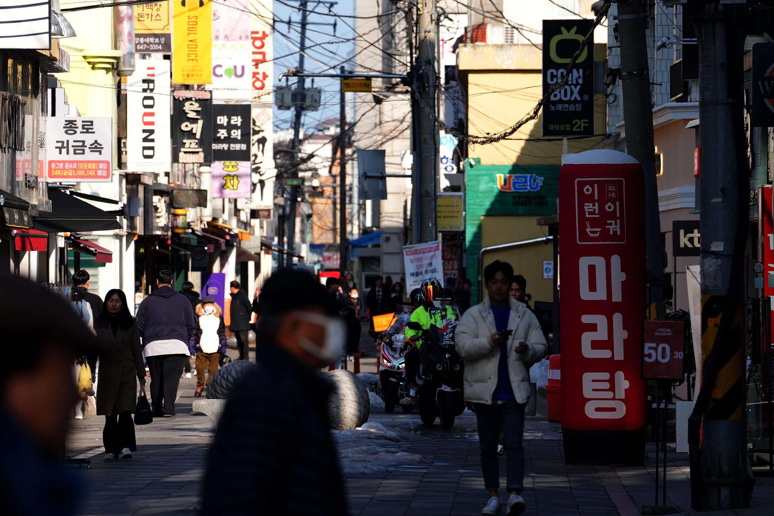 Dienvidkorejas pilsētas iela ar gājējiem un korejiešu izkārtnēm.