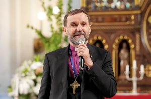 Luterāņu arhibīskaps Jānis Vanags runā, turot mikrofonu.