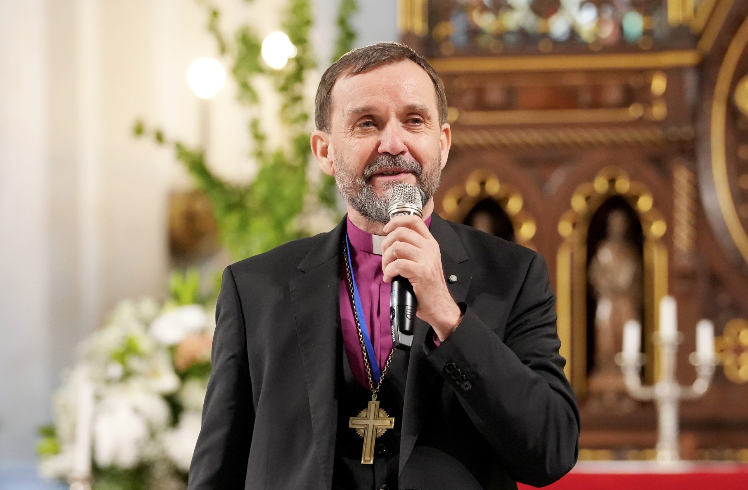 Luterāņu arhibīskaps Jānis Vanags runā, turot mikrofonu.