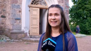 Jauna sieviete sniedz interviju pie Mazirbes baznīcas