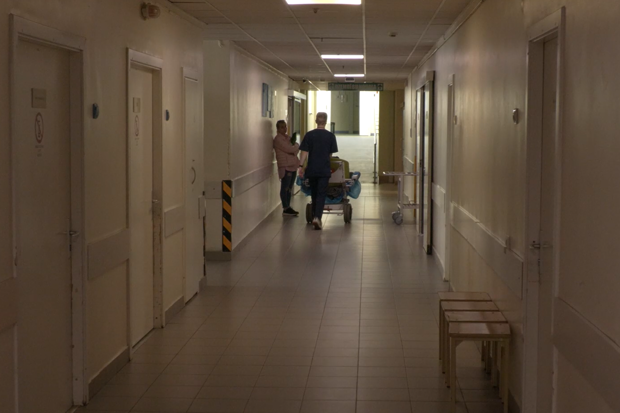 Slimnīcas gaitenis ar medicīnas darbinieku un pacientu