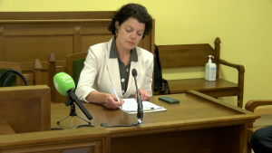 Apsūdzētā Ieva Raubiško sēž pie galda.