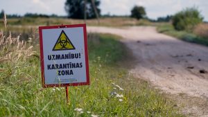 Brīdinājuma zīme par karantīnas zonu pie lauku ceļa.
