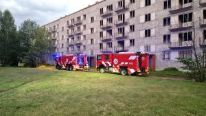 Ugunsdzēsēju automašīnas pie pamestas daudzdzīvokļu ēkas ugunsgrēka laikā