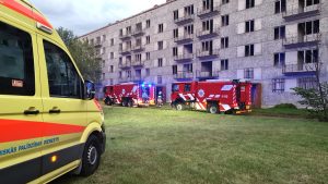 Ugunsdzēsēji ar automašīnām pie pamestas ēkas ugunsgrēka laikā