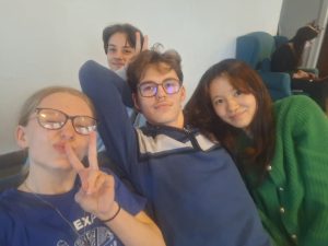 Četri jaunieši, kas sēž uz dīvāna, uzņem selfiju
