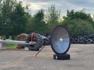 Satelītšķīvis un metāla konstrukcija industriālā teritorijā ar traktora riteni
