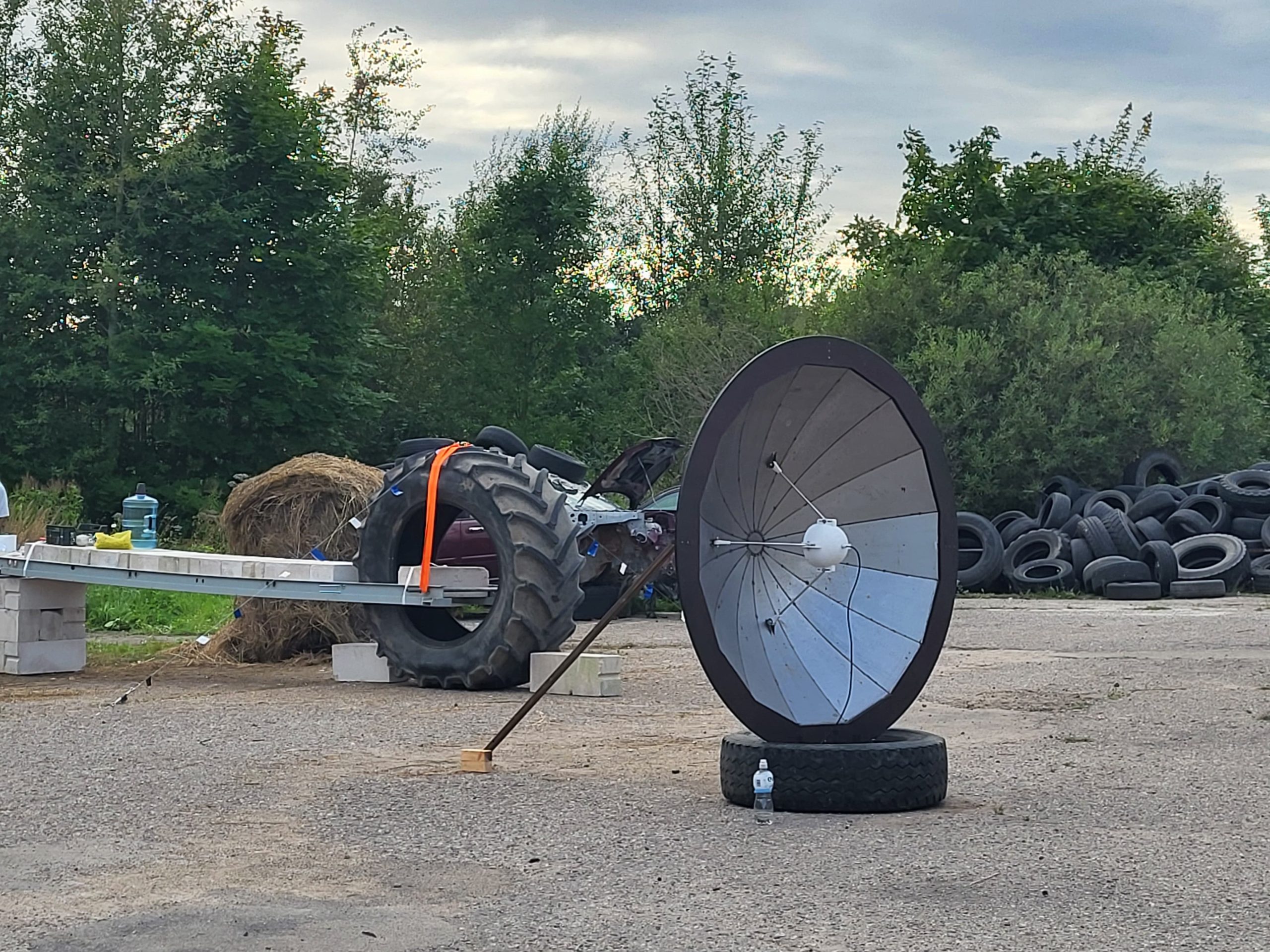 Satelītšķīvis un metāla konstrukcija industriālā teritorijā ar traktora riteni