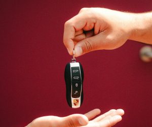 Cilvēks nodod Porsche automašīnas atslēgas otrai personai