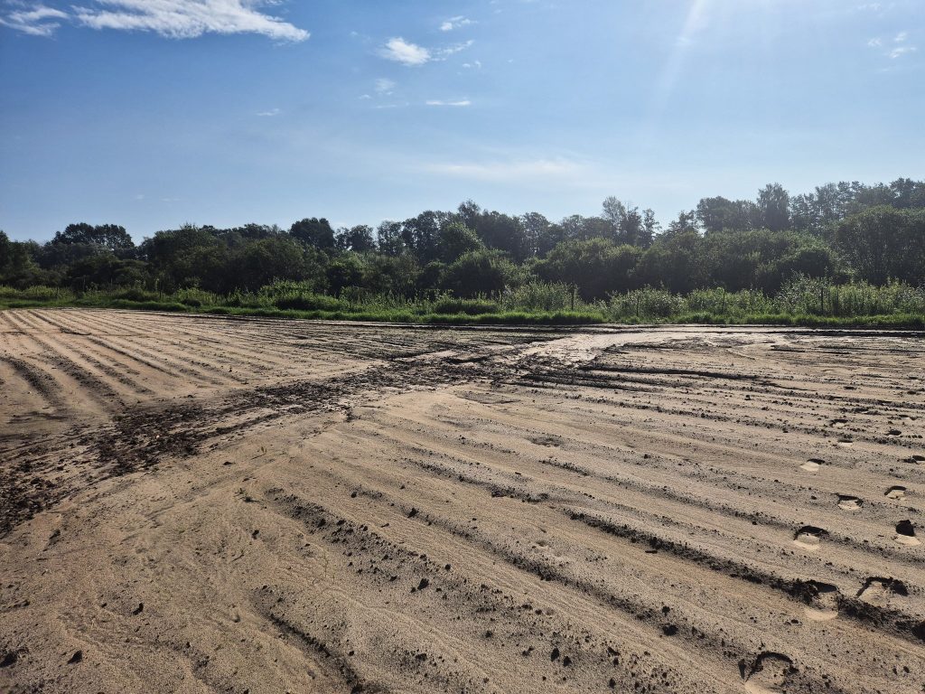 Applūdis smilšains lauks ar dubļu riepu pēdām