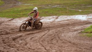 Motokrosa braucējs dubļainā trasē ar motociklu