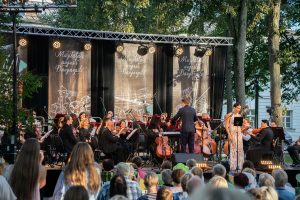 Diriģents vada orķestri un soliste dzied brīvdabas koncertā "Muzikālais augusts Daugavpilī"