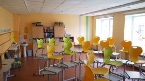 Tukša klase ar sakrautiem krēsliem uz galdiem mācību iestādē