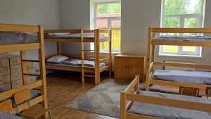 Skolas internāta istaba ar divstāvu gultām un skatu uz pagalmu