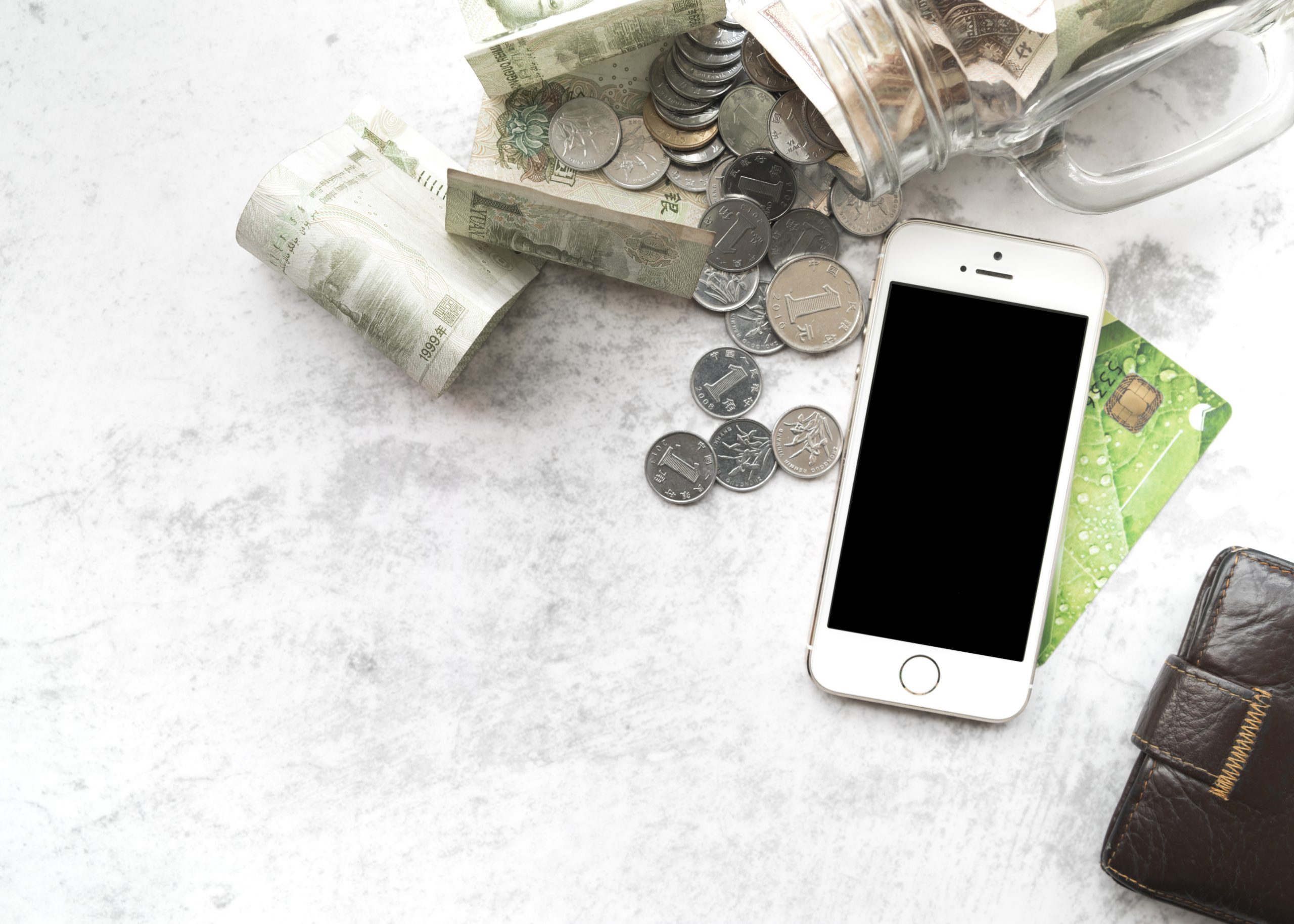 Telefons, nauda un bankas karte uz galda – finanšu un drošības simbols.