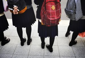 Skolēni skolas formās ar mugursomām