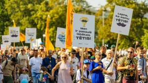 Cilvēki gājienā ar plakātiem, kas veltīti Tēva dienai.