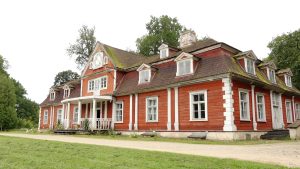 Ungurmuižas koka baroka muižas ēka ar sarkaniem sienu dēļiem un baltām apmalēm