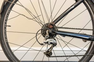 Velosipēda aizmugurējais ritenis ar bojātu pārslēdzēju un apkopi nepieciešamām detaļām