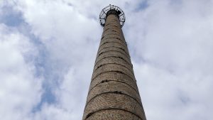 Vecā rūpnīcas ķieģeļu skursteņa tornis pret debesīm