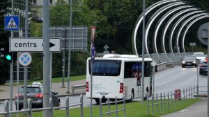 Sabiedriskais autobuss brauc pāri tiltam uz pilsētas centru