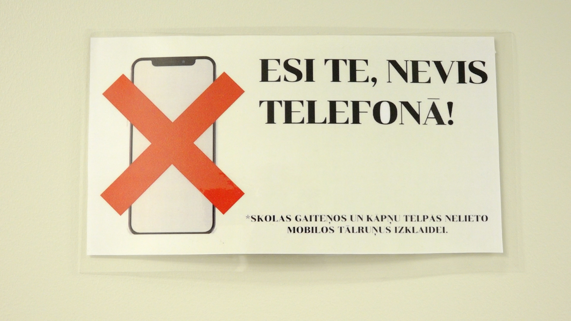 Skolas plakāts ar aizliegumu lietot telefonus – “Esi te, nevis telefonā!”