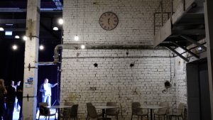 Industriāla telpa ar baltu ķieģeļu sienu un pulksteni
