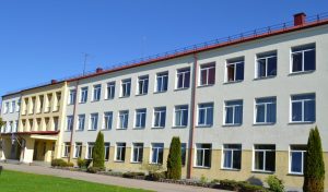 Aglonas vidusskolas ēka saulainā dienā ar sakoptu apkārtni.