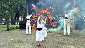 Baltu vienības dienas atklāšanas uguns priekšnesums Jaunjelgavā ar dejotājiem baltos tērpos un uguns rekvizītiem.