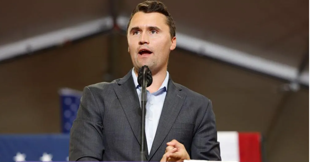 Čārlijs Kērks runā publiskā pasākumā pie mikrofona.