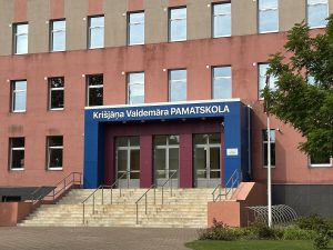 Ventspils Krišjāņa Valdemāra pamatskolas ēkas fasāde ar skolas nosaukuma uzrakstu virs ieejas.