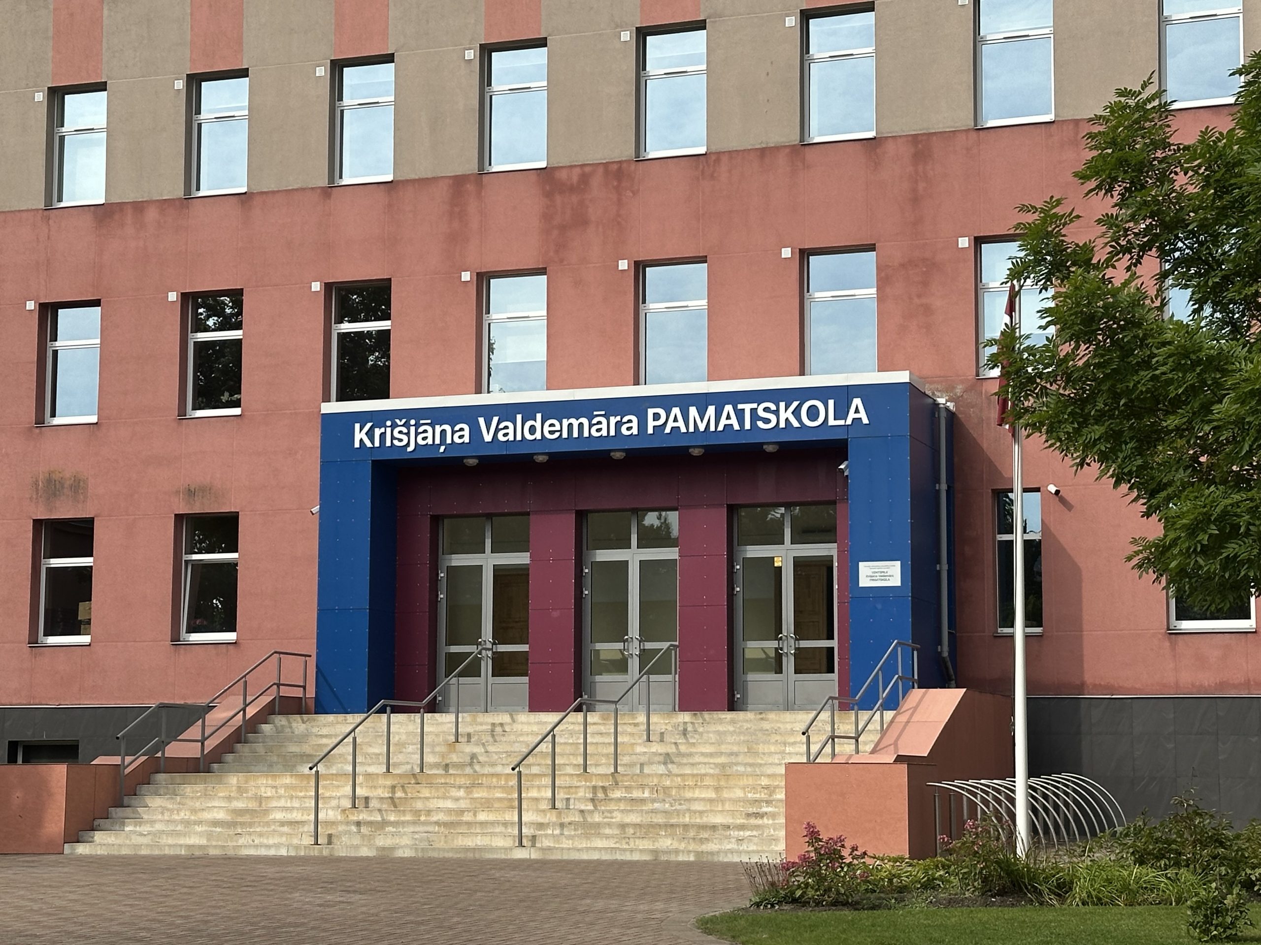 Ventspils Krišjāņa Valdemāra pamatskolas ēkas fasāde ar skolas nosaukuma uzrakstu virs ieejas.