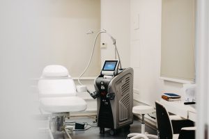 Lāzertehnoloģiju iekārta un pacienta kušete estētiskās medicīnas kabinetā