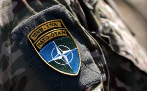 Latvijas karavīra formā uzšuve ar NATO emblēmu.