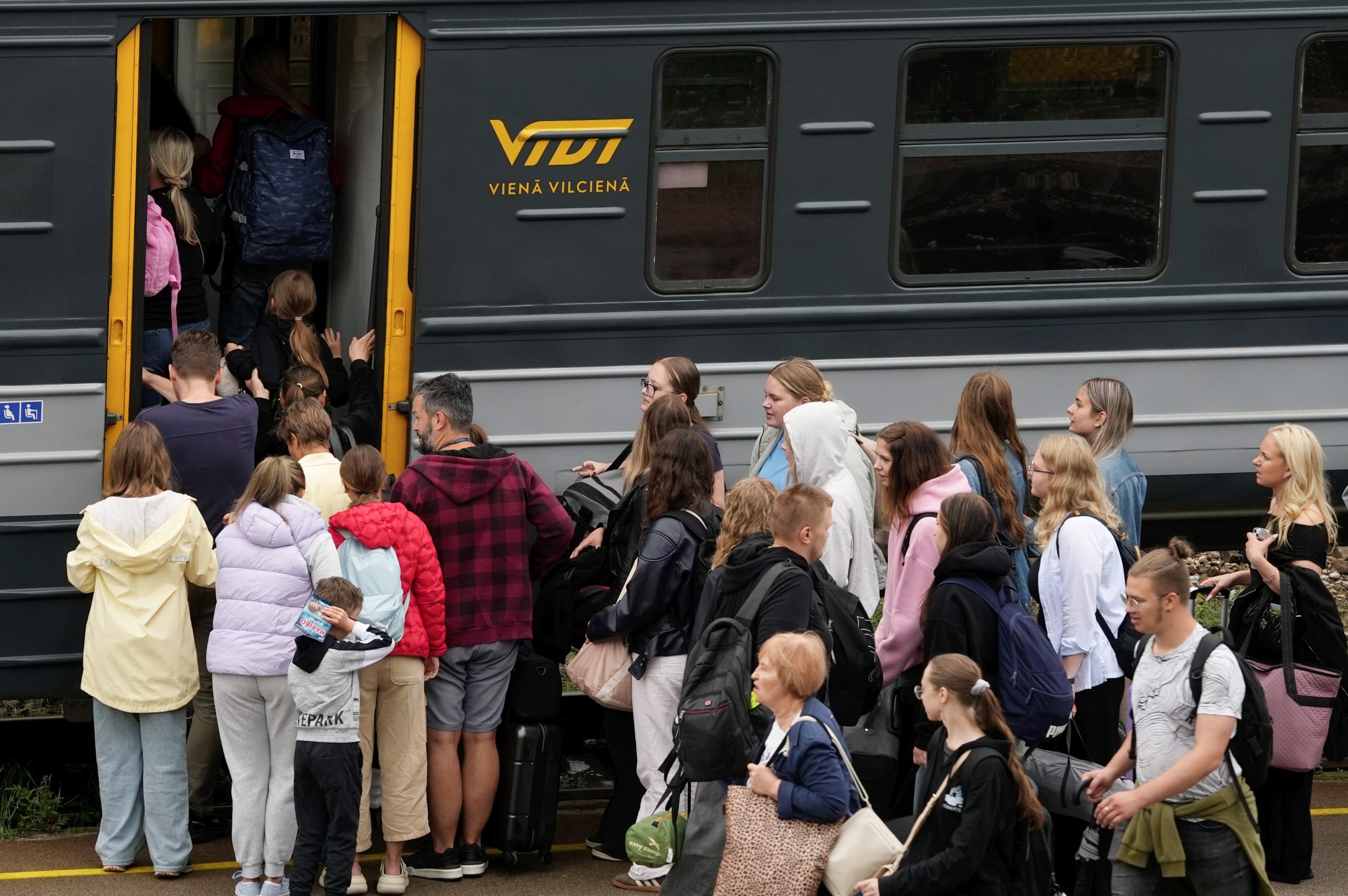 Cilvēku grupa kāpj vilcienā.