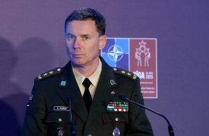 Latvijas Nacionālo bruņoto spēku komandieris, ģenerālmajors Kaspars Pudāns, militārajā formastērpā runā pie pults ar NATO/Rīgas samita logo fonā.