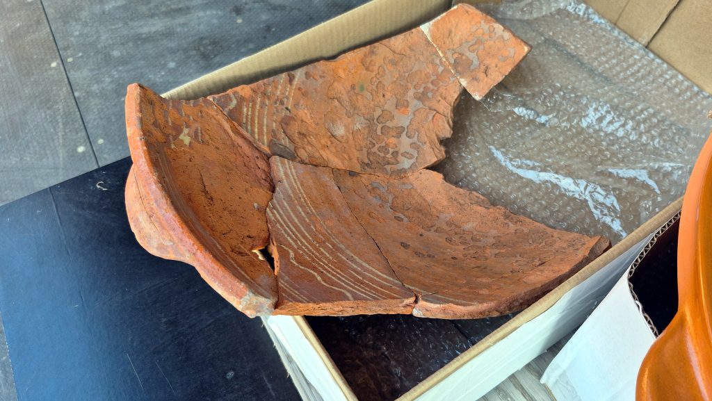 Saplīsuša māla poda fragments ar svītrainu rakstu.