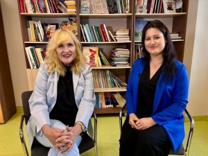 Divas sievietes sarunājas studijas vidē ar grāmatām fonā, gatavojoties veselības raidījumam ReTV.