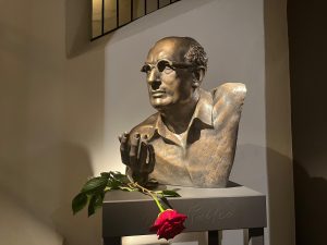 Bronzā veidots Marka Rotko krūšutēls ar rozi pie pjedestāla Daugavpils Rotko muzejā.