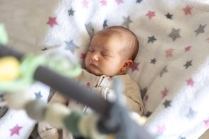 Jaundzimušais bērniņš guļ ietīts segā ar zvaigznīšu rakstu.